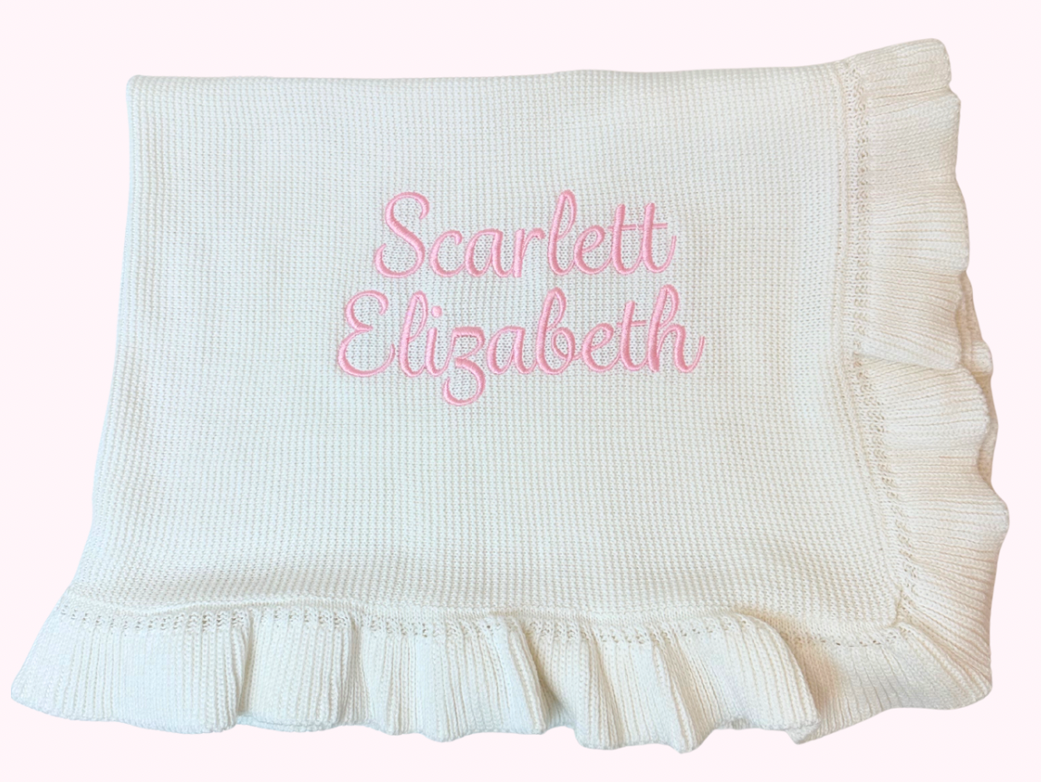 White baby blanket with soft ruffle edge and embroidered name with pink thread