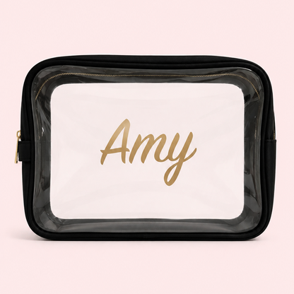 A personalized clear plastic cosmetic bag with a black zipper and nylon thick border personalized with gold script permanent vinyl.