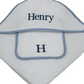 White hooded baby towel with blue gingham trim and embroidered name 'Henry' on a white background. 100 % terry cotton