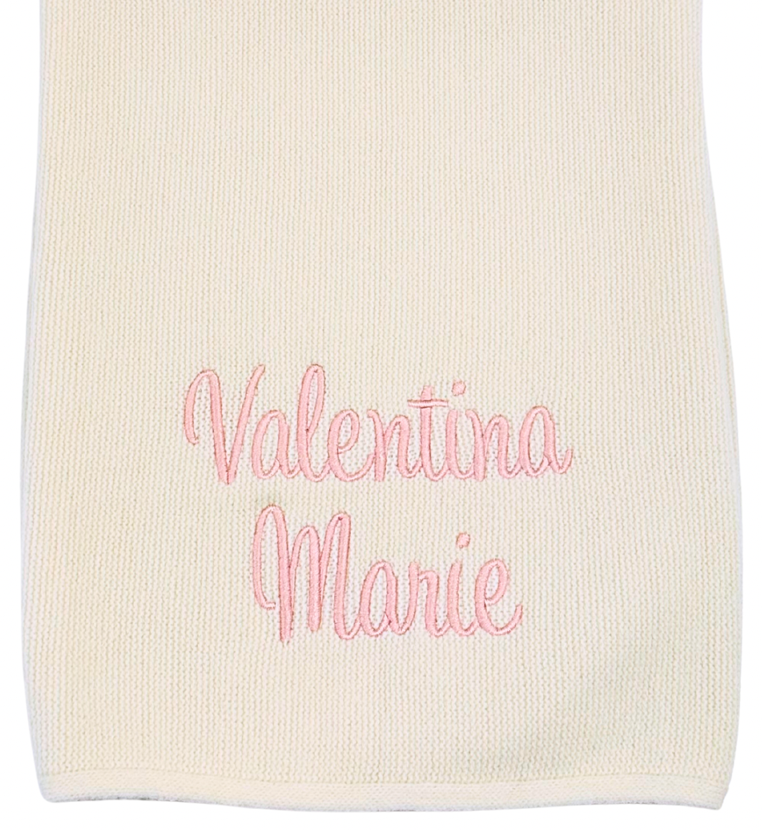 White blanket with pink embroidered text on a white background